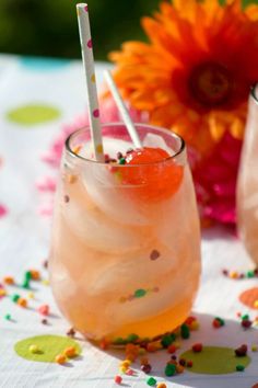 two glasses filled with drinks sitting on top of a table covered in confetti