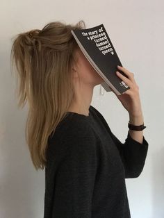 a woman holding a book up to her face