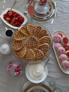 a table topped with waffles covered in icing next to plates of food