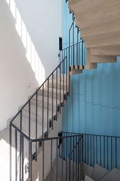 a stair case in front of a blue wall with metal railings and handrails