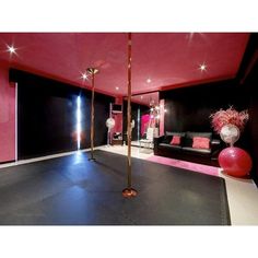 a room with black and pink walls, white flooring and two tall gold poles