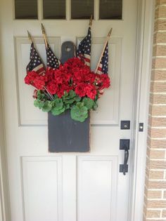 a patriotic door hanger with red flowers and american flags on the front door,