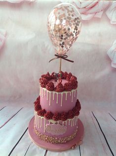 a three tiered cake decorated with pink icing and red roses, topped with a balloon