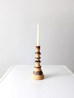 a tall wooden candle holder sitting on top of a white table