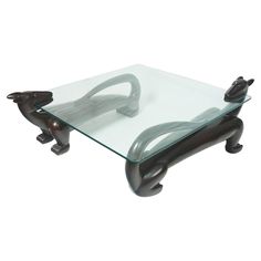 a glass and metal coffee table with two cats on it's legs in the shape of an animal