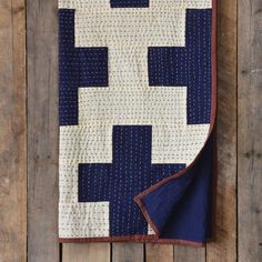 a blue and white quilt hanging on a wooden wall