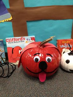 two pumpkins with faces on them sitting next to books and a stuffed animal dog