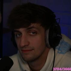 a young man wearing headphones in front of a microphone and looking at the camera