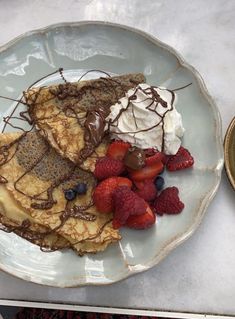 a plate topped with pancakes covered in chocolate and strawberries