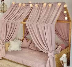 a canopy bed with pink curtains and lights on the ceiling, in a girls'bedroom