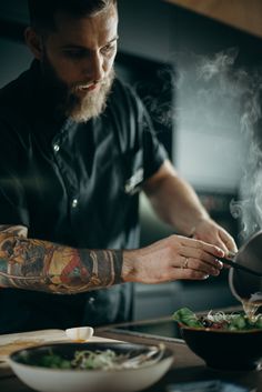 a man with tattoos cooking in a kitchen