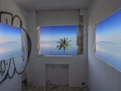 an abandoned bathroom with graffiti on the walls and palm tree in the window looking out