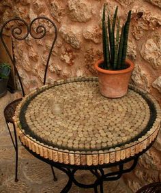 a potted plant sitting on top of a small table next to a stone wall