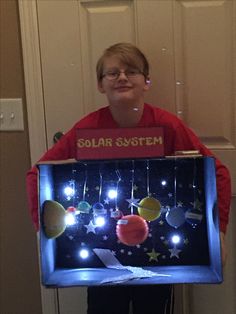 a boy holding up a solar system with lights on it's sides and the words solar system in front of him