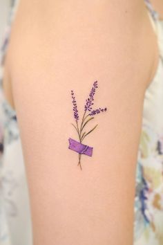 a woman's tattoo with lavender flowers on her left arm and purple ribbon in the middle