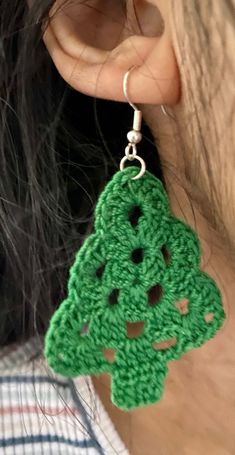 a close up of a person wearing green crochet earrings