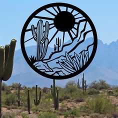 a metal sculpture in the shape of a desert scene with cactus and mountains behind it