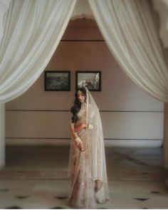 a woman standing in front of a doorway wearing a white veil and holding a bouquet