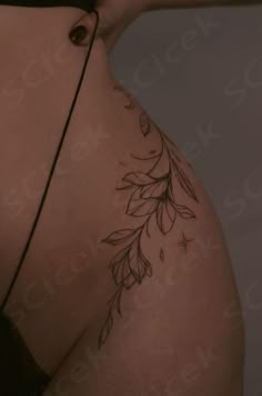 the back of a woman's stomach with leaves on it and an arrow tattoo