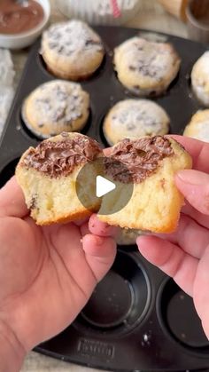 a person holding a half eaten chocolate chip cookie in front of muffin tins