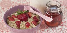 a pink bowl filled with oatmeal and strawberries