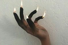 someone is holding out their hand with two fingers that are shaped to look like flames