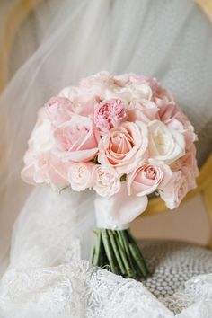 a bridal bouquet sitting on top of a white chair next to a lace covered pillow