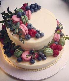 there is a cake decorated with berries and macaroons