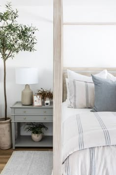 a bedroom with a bed, nightstand and potted plant