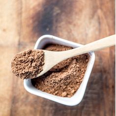 a wooden spoon filled with cocoa powder on top of a table