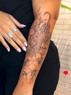 a woman's arm with a leopard and flowers tattoo on it