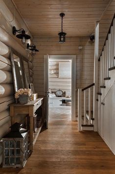 a long hallway leading to a living room and dining area with wood floors, white walls and wooden stairs