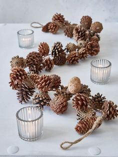 pine cones and votives are arranged on a table