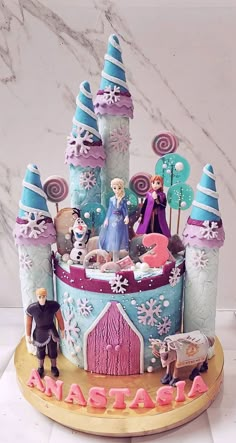 a birthday cake with frozen princess figures on top and decorations around the base, including an ice castle