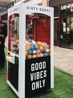 an old fashioned gummy machine with balls in it's display case on the grass