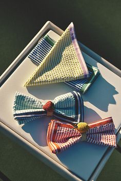 three different colored bow ties sitting on top of a white tray