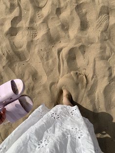 a person laying in the sand with their feet up on a towel and flip flops