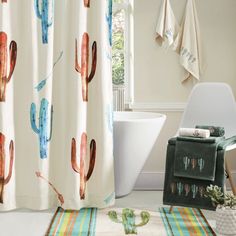 a bathroom with cactus shower curtain, rug and bathtub in the corner next to it