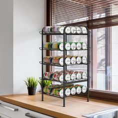 a kitchen counter with a rack full of canned food on it and a potted plant in the window sill