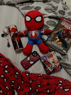 a spiderman stuffed animal laying on top of a bed next to books and magazines