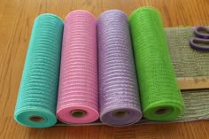 four rolls of colorful fabric sitting on top of a wooden table