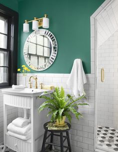 a bathroom with green walls and white tiles on the floor, along with a plant