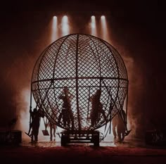 a group of people standing in front of a large metal ball with lights on it