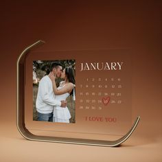 a personalized glass photo frame with a couple kissing in front of it and the date is