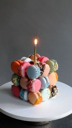 a white plate topped with a cake covered in lots of different colored candies and a lit candle