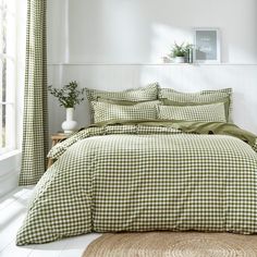 a green and white checkered comforter set on a bed in a room with windows