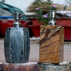 two soap dispensers sitting on top of some stone blocks next to each other