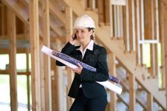 a woman in a hard hat talking on a cell phone while holding a blueprint