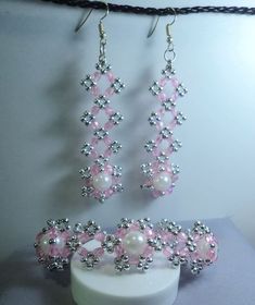 a pair of pink and white beaded earrings next to a cup with milk in it