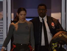 a man and woman standing next to each other in front of a fireman's suit case